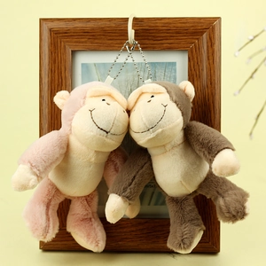 Gros plan de porte-clés singes en peluche rose et marron dans un cadre en bois