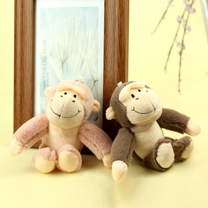 Détail de porte-clés singe en peluche rose et marron avec boucles sur surface chaude
