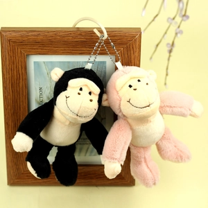 Détail de deux porte-clés gorille en peluche noir et rose sur un cadre en bois