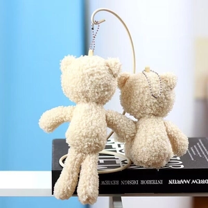 Close-up of two cream plush teddy bear charms with soft lamb wool texture and bead chains