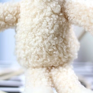 Macro shot of soft plush bear pendant with thick lamb wool texture and creamy white fur