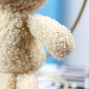 Close-up of the soft curly plush texture and fine stitching on the teddy bear charm