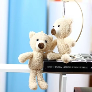 Detail of cute cream plush teddy bear keychains with soft curly fur and gold metal hooks