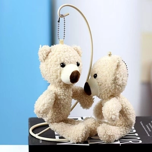 Close-up of two creamy white curly teddy bear plush pendants with metal ball chains