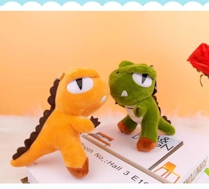 Close-up of plush dinosaur charms in orange and green with golden bead chains