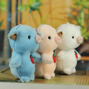 Detailed view of three colorful plush pig keychains with cute strawberry accessories