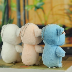 Detailed view of three soft plush pig charms in white, pink, and blue with metal chains