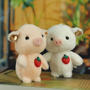 Close-up of cute plush pig pendants with soft fur, golden ears, and strawberry details