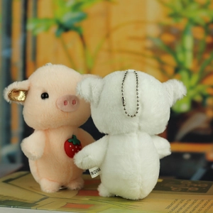 Close-up of plush pig keychains with strawberry detail and metal bead chains