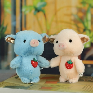 Close-up of pink and blue plush pig charms with sequin ears and strawberry details