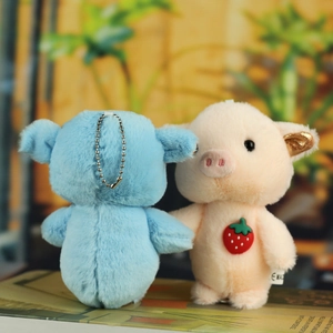 Close-up of cute plush pig keychain charms with strawberry detail and metal ball chains