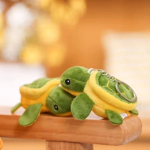 Macro detail of cute green and yellow plush turtle keychain set on wooden surface