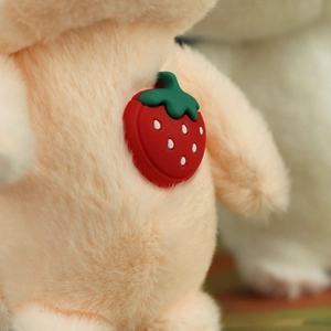 Close-up of fluffy plush pig charm with a detailed red strawberry silicone accessory