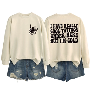 Front and back detail of cream crewneck sweatshirt with black tattoo graphic and bold text