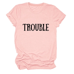 Dettaglio in piano di una t-shirt in cotone rosa con scritta TROUBLE in stile retrò