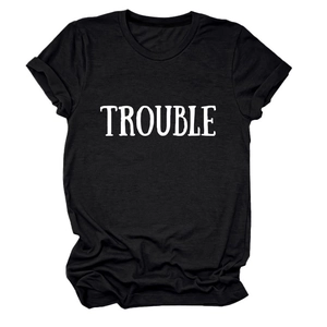 Dettaglio di una t-shirt nera in cotone con stampa a lettere TROUBLE bianche sul petto