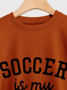 Detail des karamellorangen Rippausschnitts und Fußballdrucks auf dem Baumwoll-Sweatshirt