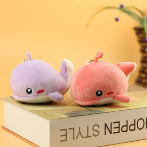 Close-up of soft plush whale keychains in pink and purple with gold chains