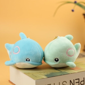 Detail of blue and green plush whale keychains with embroidery on a book