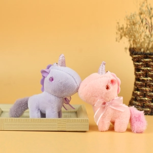 Detail of pink and purple plush unicorn toys with glitter horns and soft fabric texture