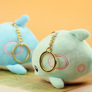 Close-up of soft whale plush pendants with golden keychains and fine embroidery
