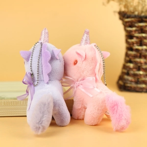 Detail of cute plush unicorn charms in pink and purple with shiny horns and silk bows