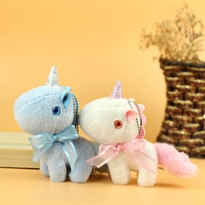 Close-up of plush unicorn charms in blue and cream with glitter horns and satin bows