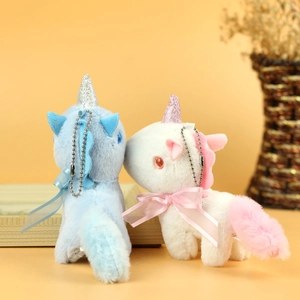 Close-up of blue and white plush unicorn keychains with glitter horns and silk bows