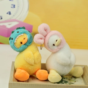 Detail of plush duck keychains with cute dinosaur and rabbit hoods in a wooden tray