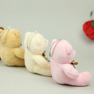 Detailed side view of plush teddy bear charms in pink, beige, and light brown with golden bows