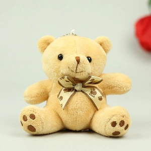 Detailed view of a plush teddy bear pendant with a dark footprint pattern bow tie