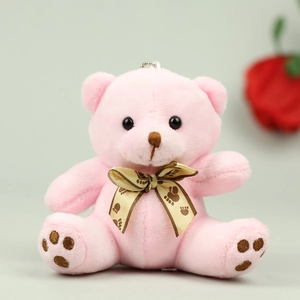Detail of pink plush teddy bear pendant with golden bow and soft fluffy texture