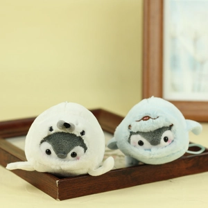 Close-up of cute plush penguin keychains with soft shark and seal disguises in a tray