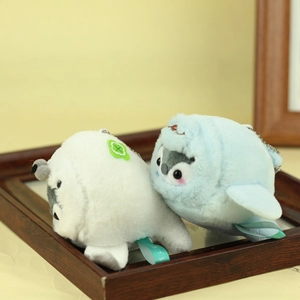 Detail of plush whale and penguin keychain pendants with metal chains in a wood frame