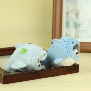Detailed view of two blue plush penguin keychains with shark hoodies and clover embroidery