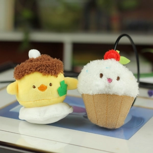 Close-up of plush chick and cupcake pendants with soft cream and cherry details