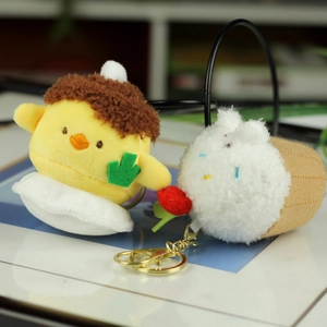 Detail view of plush strawberry cheesecake and chick pendants with gold lobster clasps