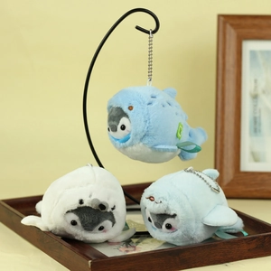 Three plush penguin charms in shark and seal costumes hanging on a metal display stand