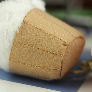 Macro detail of plush strawberry cheesecake pendant with brown felt and gold keychain