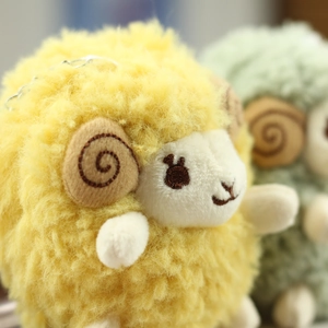 Macro detail of a yellow plush sheep pendant with soft curls and metal bead chain