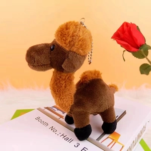 Detail of cute brown plush camel keychain with silver bead chain on white prop book
