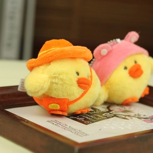Detail of plush yellow chick keychains with cute hats and backpacks in a wooden frame