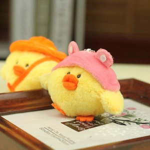 Detail of plush yellow chick keychains with cute hats and metal chains in a cozy setting