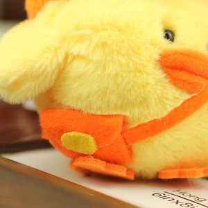 Close-up of soft yellow plush chick pendant featuring a tiny orange backpack detail