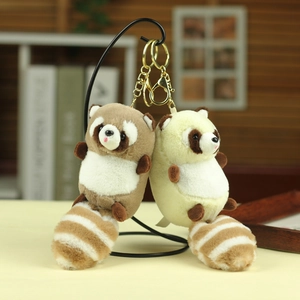 Close-up of cute raccoon plush keychains in brown and beige with gold metal hooks
