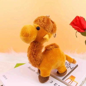 Cute yellow plush desert camel keychain hanging on a white book with a red rose