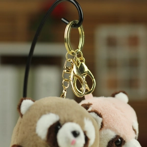 Detailed close-up of golden metal keychains and fluffy raccoon plush heads with soft texture