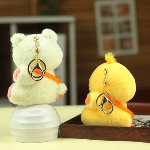Detail of plush cream bear and yellow duck keychains with golden rings on a display stand