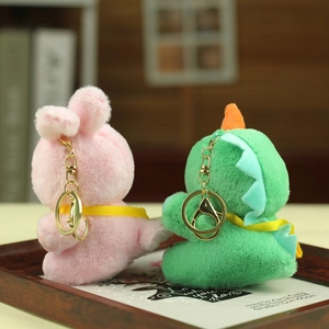 Detail of plush bunny and dinosaur keychain with soft fur texture and golden metal clasp