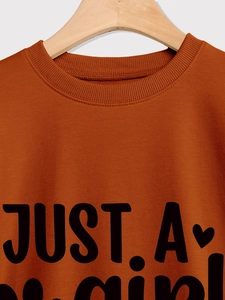 Detail of ribbed crew neck and printed slogan on caramel orange sweatshirt fabric